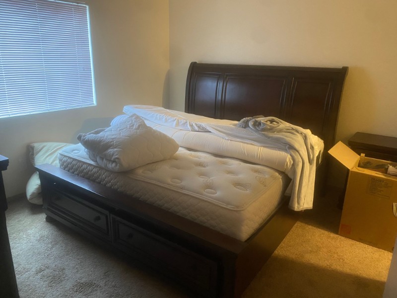 Image of an emerald green couch in an empty room with hardwood floors and a white wall